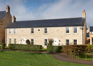 A small terrace of two-storey cottages with stone exterior and slate roofs.