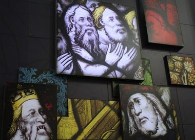 Image showing a display board at a temporary exhibition in York Minster showcasing the conservation work to the Great East Window. It shows some images from the stained glass of the window.
