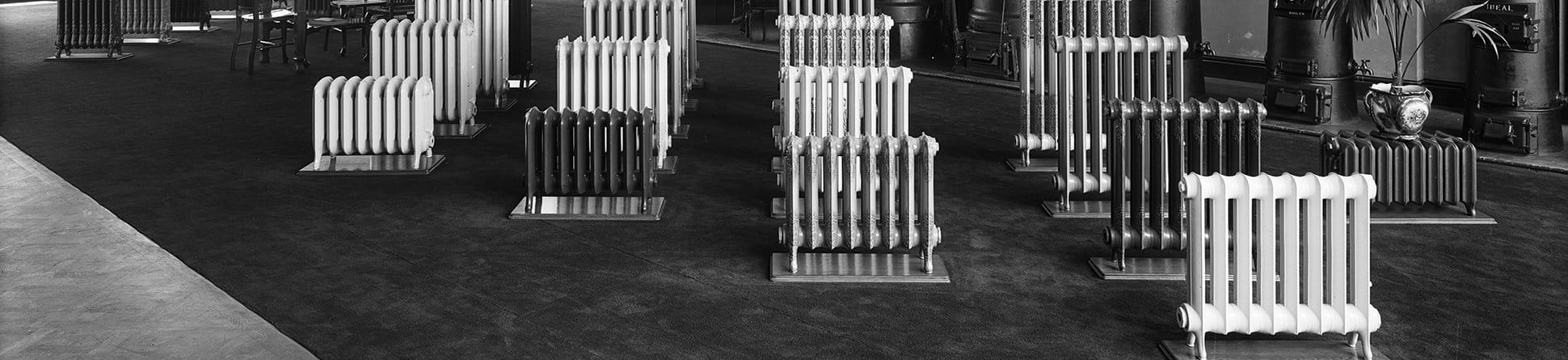 black and white photo of a large showroom with numerous radiators on central display.