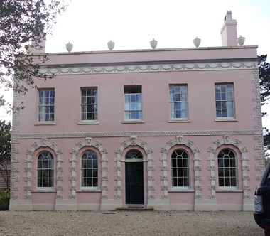 Two-storey stuccoed front building painted in pale pink.