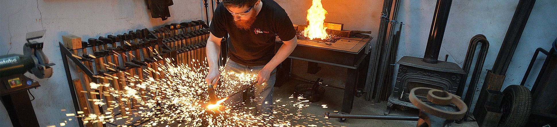 A blacksmith hammering metal and causing sparks to fly.