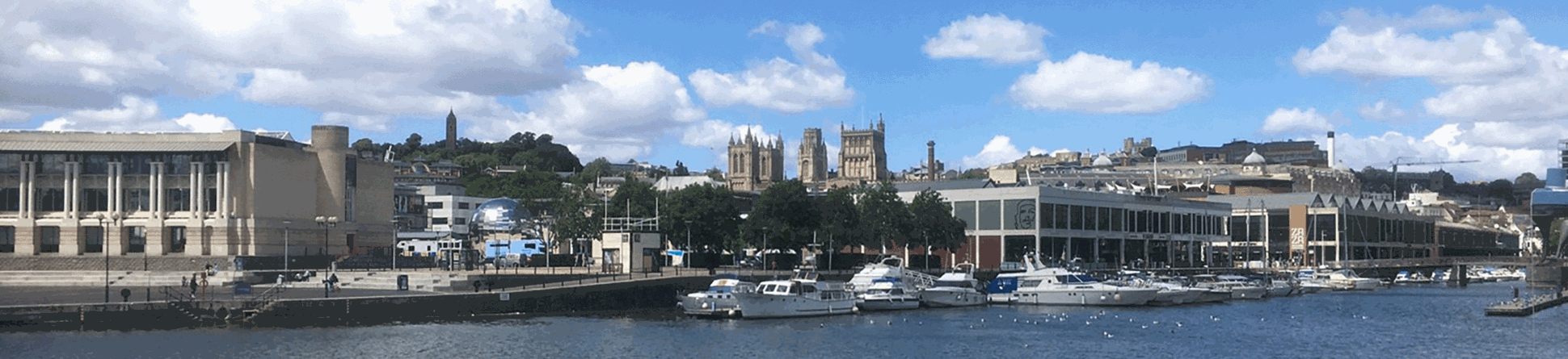 A view across the river towards Bristol's harbourside buildings. The towers of Bristol Cathedral can be seen rising above in the middle ground.