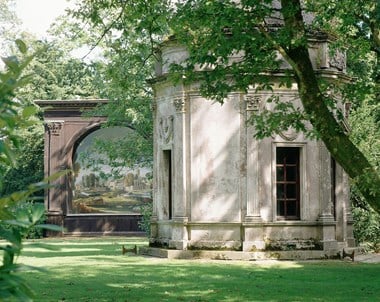 The 1895 Singing Theatre (seen behind the Roman Temple) with its painted back-drop depicting a pastoral landscape, set in the (real) landscape of Larmer Tree Grounds, in Dorset.