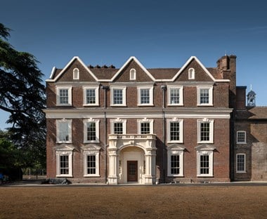 A large brick manor trimmed with off-white moulding, set in grounds.