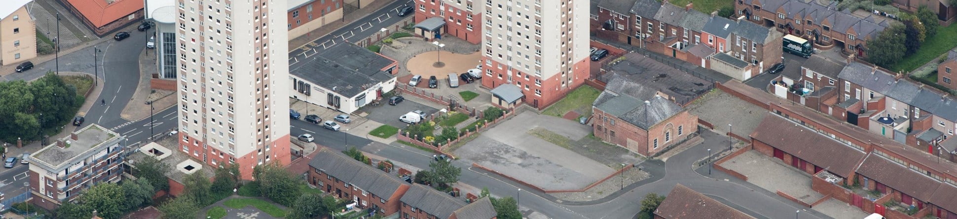 Aerial view of Phoenix Hall and three nearby tower blocks in Sunderland. The top left corner shows the shoreline and boats.