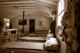 Colour photograph showing interior of wooden hut with beds around sides