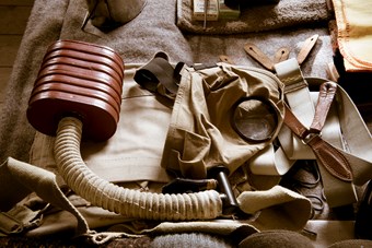 Colour photograph showing a close-up of soldiers kit with old-fashioned gas mask