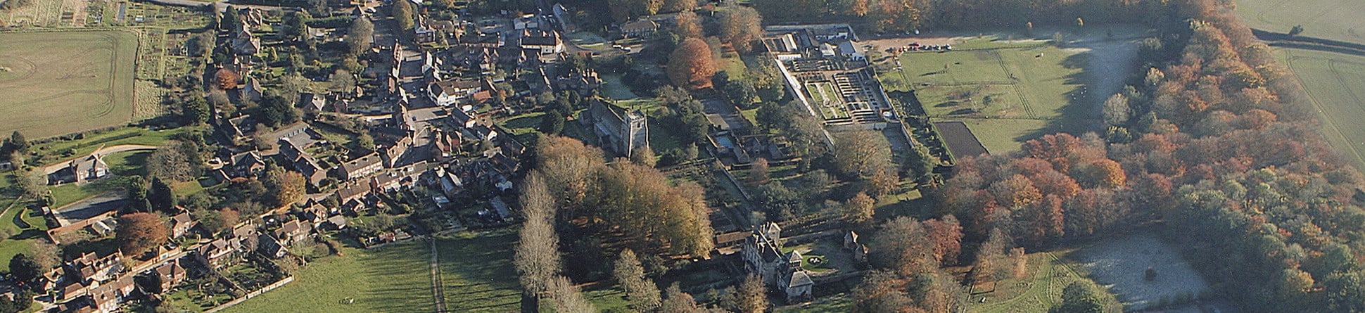 Colour aerial photo showing a village centre with a church, manor house and houses bordering a central market square