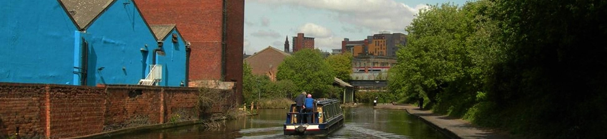 View along a canal in Birmingham, with canal boat and industrial buildings.