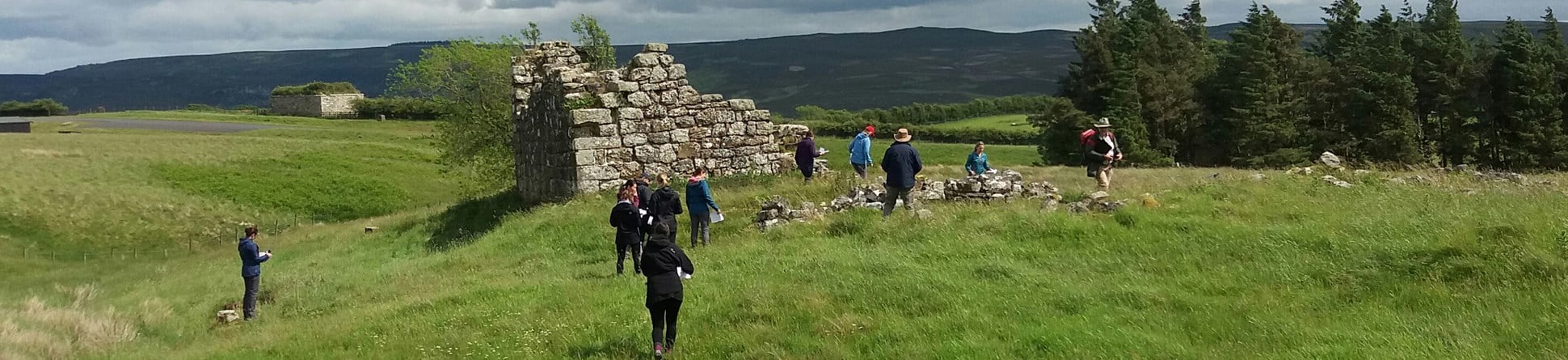 Several PhD students investigating a ruined bastle in the Northumberland landscape