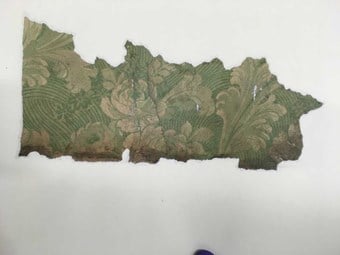 A fragment of historic wall paper with a floral pattern. The green pigment contains arsenic.