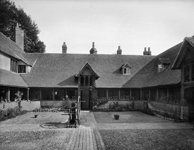 The exterior of the almshouses at Ewelme, founded in 1437 by the Earl and Countess of Suffolk, showing a cloister walk built around a quad. 