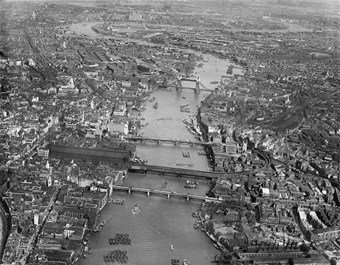 Archive aerial photograph looking along the river showing London Bridge, Tower Bridge and the city.