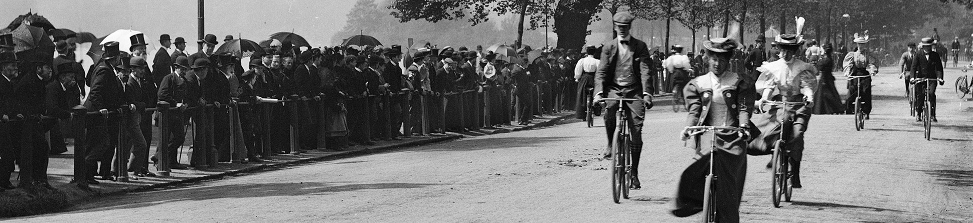 Archive photograph of male and female cyclists in Hyde Park with spectators lining the route.
