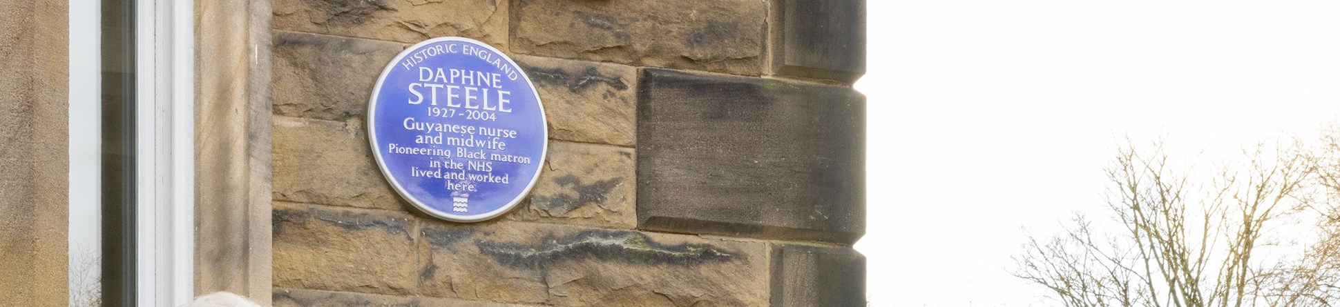 A blue heritage plaque on a brown stone wall