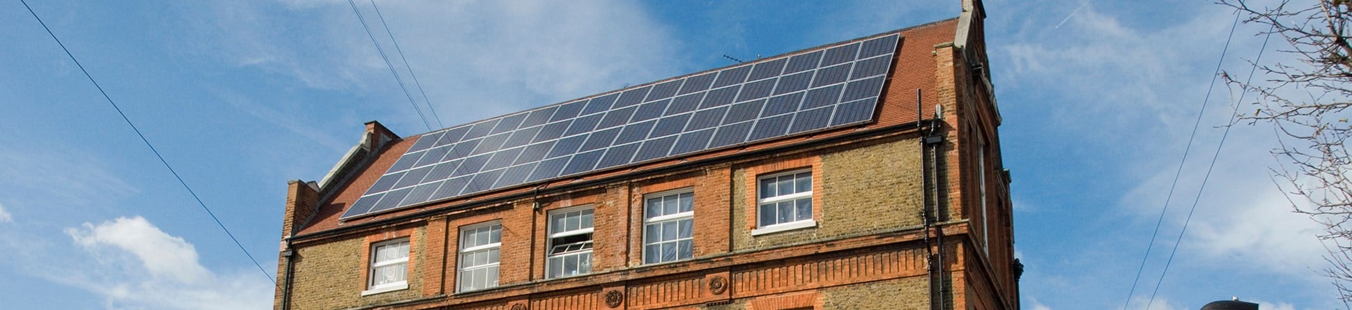 Solar panels on the red tile roof of a brick building.