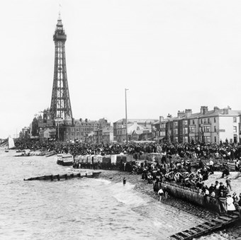 Blackpool’s beach has disappeared at high tide, but the crowds still gather on the sloping sea defences.