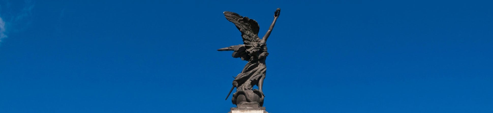 A war memorial with a winged victory atop a pillar, at the base is a group of statues representing different branches of the British armed services, in this image a sailor is prominent.