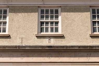 The front of a building showing three sash windows above a plaque to King George VI and the date 1939.