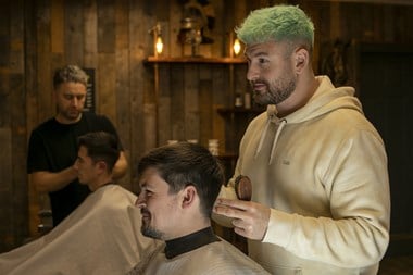 Two barbers at work on their customers.
