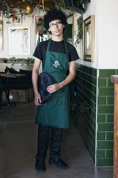 Portrait of a waiter holding a tray by his side at a bistro.