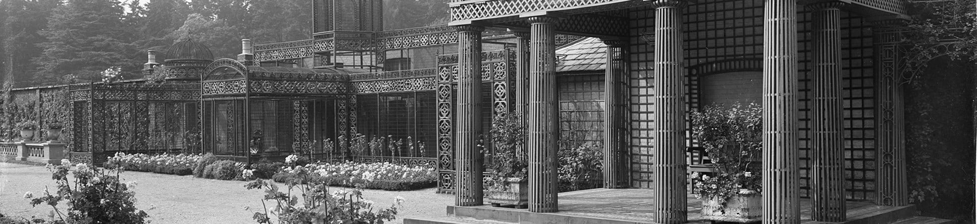 archive black and white photograph of a classical style colonnaded garden building and an elaborate wrought-iron aviary