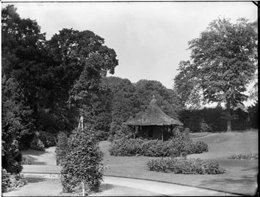 archive black and white photograph of a formal garden incorporating a thatched circular building