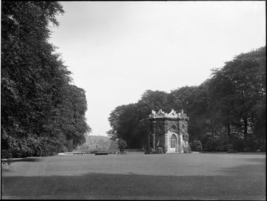 archive black and white photograph of an ivy-covered gothic-style garden building in a landscape garden