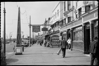 archive black and white photograph of a pavement with pedestrians