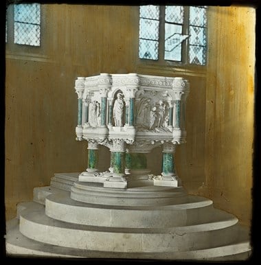 Archive photo showing a four-legged church font raised on a series of steps.