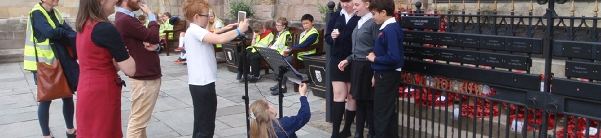 Schoolchildren and teachers filming outside a church.