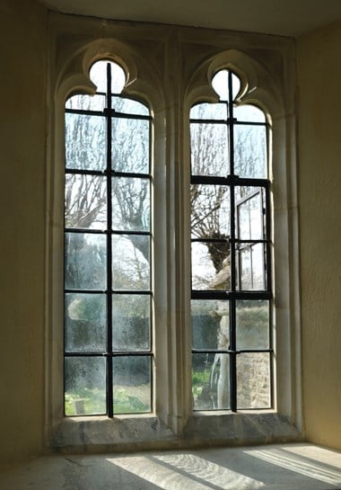 Photograph of repaired church window, from the inside, looking out onto the graveyard. 