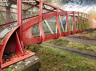 General view of a railway footbridge with red ironwork