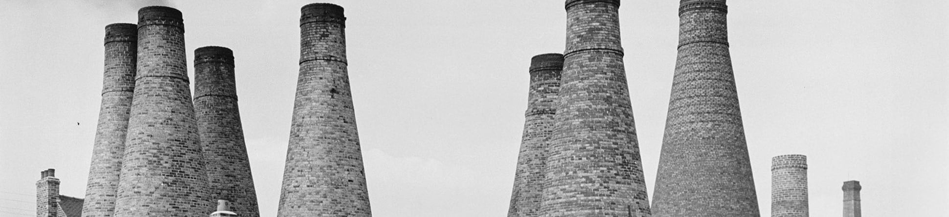 Black and white photo shows railway tracks in front of kiln chimneys