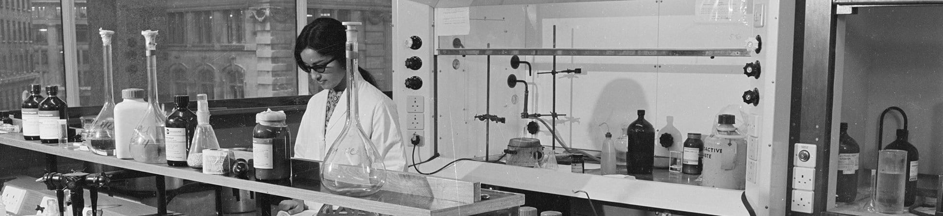 Black-and-white photograph of a female scientist at work in a laboratory at King's College London