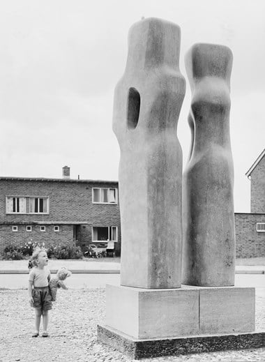Small child holding a teddy bear looking up at the sculpture Contrapuntal Forms