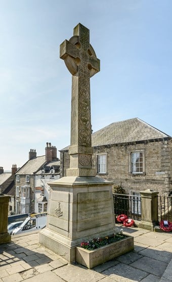 Image of Green Howards Regimental Cross, Richmond, North Yorkshire, newly listed at Grade II. A richly decorated Celtic cross stands impressively at the top of flight of stone steps. It is dedicated to the renowned Green Howards regiment which suffered thousands of losses throughout the war, including many on the first day of the Battle of the Somme. 