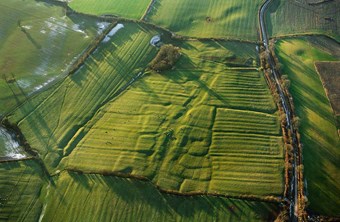 Colour aerial photo showing pasture fields with patterns of platforms and banks highlighted by low winter sunlight