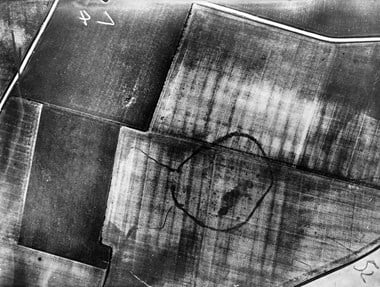 Black and white aerial photo showing an arable field with the archaeology seen as darker lines against a paler background