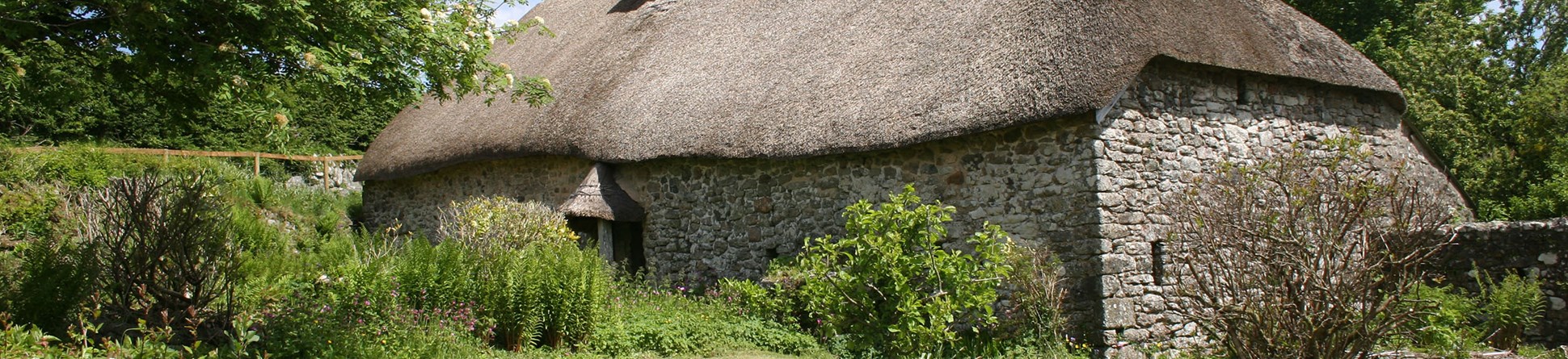 Traditional stone longhouse with thatched roof.