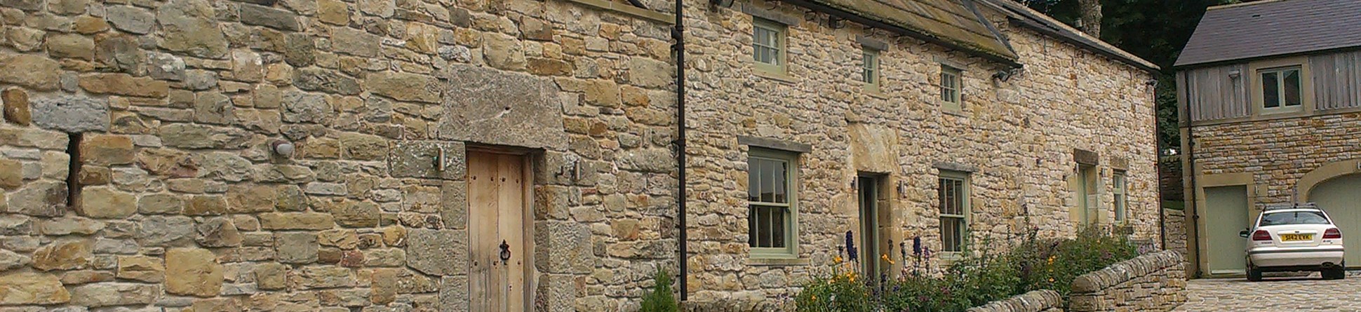 Stone farm building conversion and cobbled foreground.