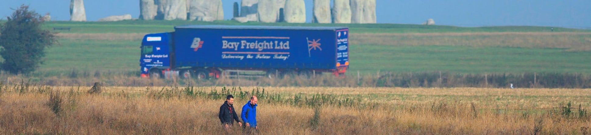 Visitors walking in Stonehenge Landscape with lorry in the background