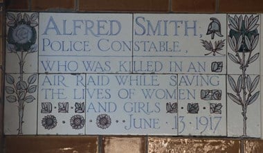 Memorial plaque to Alfred Smith, Postman’s Park, City of London, 2014. Victorian painter and sculptor George Frederic Watts conceived and executed a memorial to the ‘heroic self sacrifice’ of ordinary people. It was established in 1900 in Postman’s Park, taking the form of a loggia with a long wall of Royal Doulton ceramic plaques. This plaque is in memory of police constable Alfred Smith who was killed in a German Gotha raid of 13 June 1917 while preventing women and girls running from a factory into the street just as a bomb exploded in Finsbury, London. The same raid killed 18 children at Upper North Street School, Poplar.