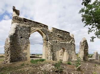 The image shows a ruined wall with an arch in the centre.