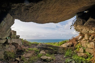 A view out to sea is framed by a large stone structure. 