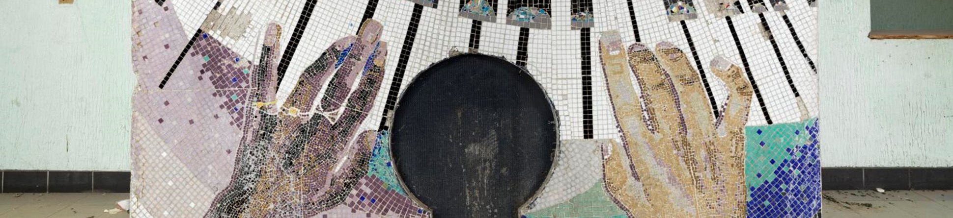 A mosaic depicting a black hand and a white hand on a piano keyboard
