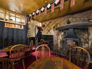 Pub lounge, showing the fireplace, seating and settle bench which is glazed at the top.