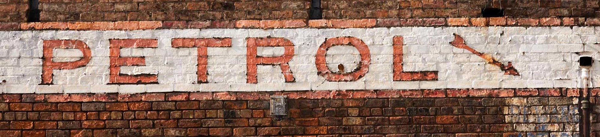 Image of a white and red sign reading 'petrol' on the front of a brick building.