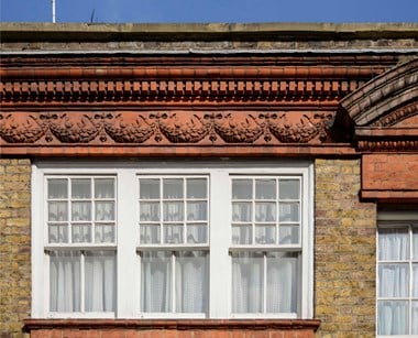 Decorative banding with swags above a three-part window.