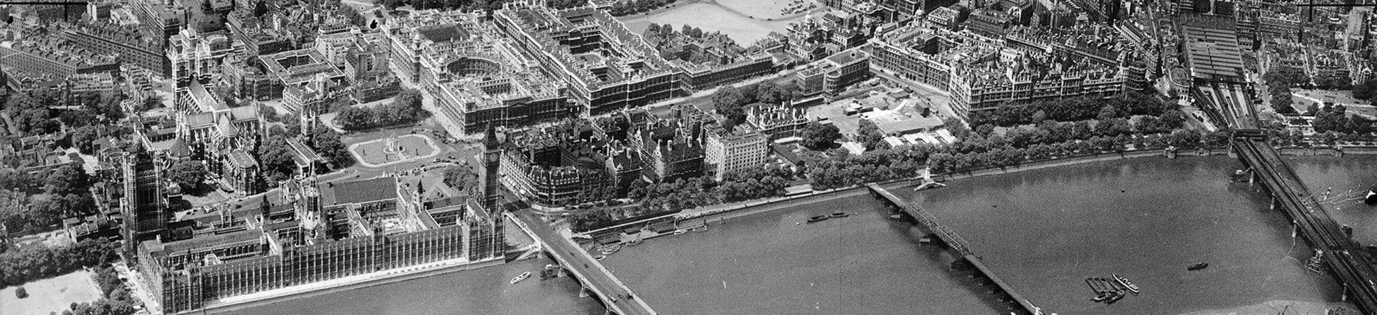 Black and white aerial photo of the Houses of Parliament and River Thames in London.